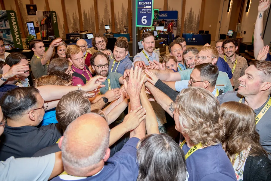 Attendees joining hands in a team huddle on the expo floor at ECRS Ignite 2026