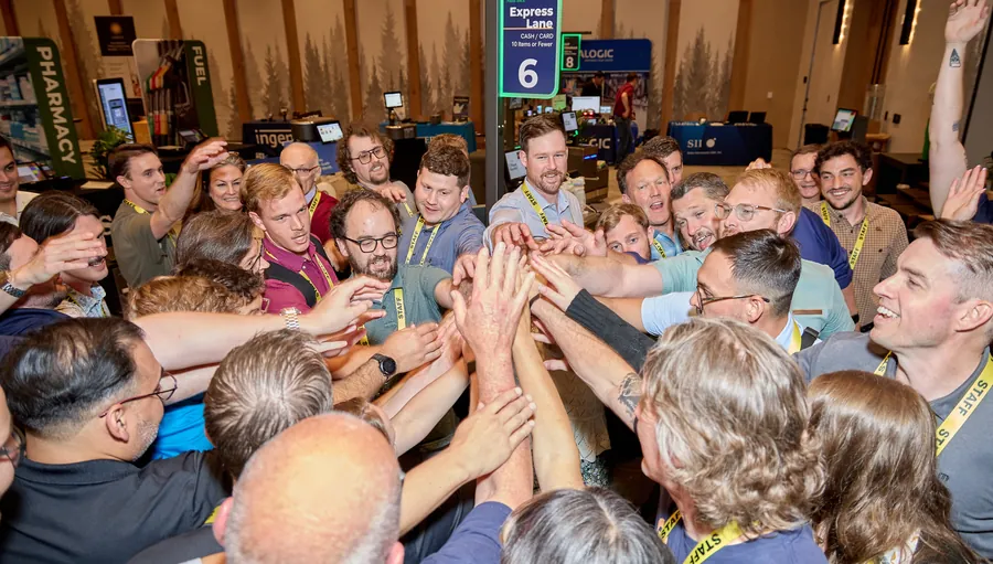 Attendees joining hands in a team huddle on the expo floor at ECRS Ignite 2026