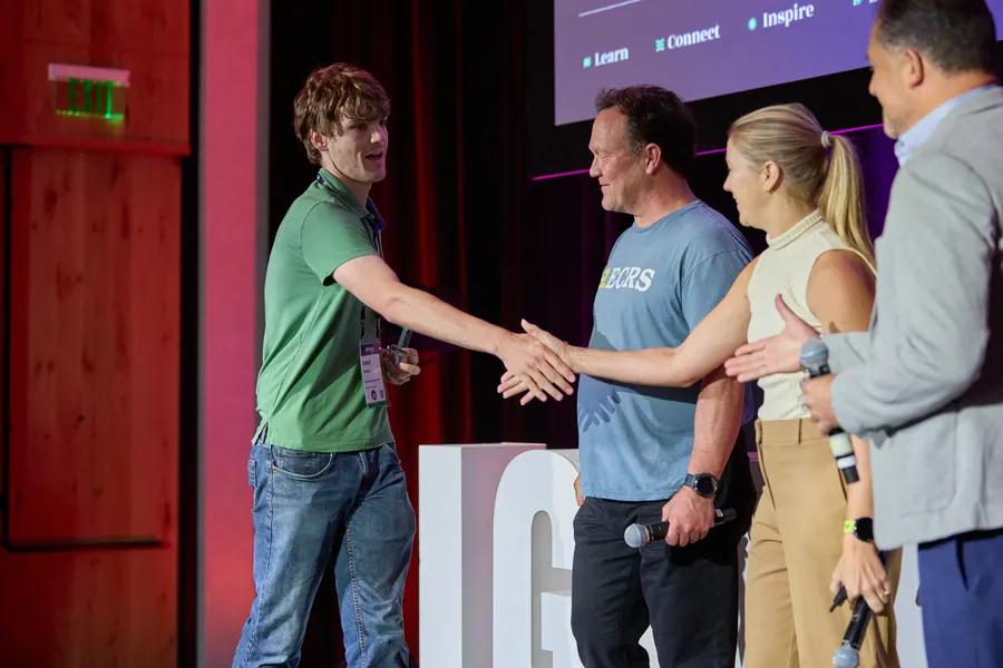 Award winner shaking hands with presenters on stage at ECRS Ignite 2026