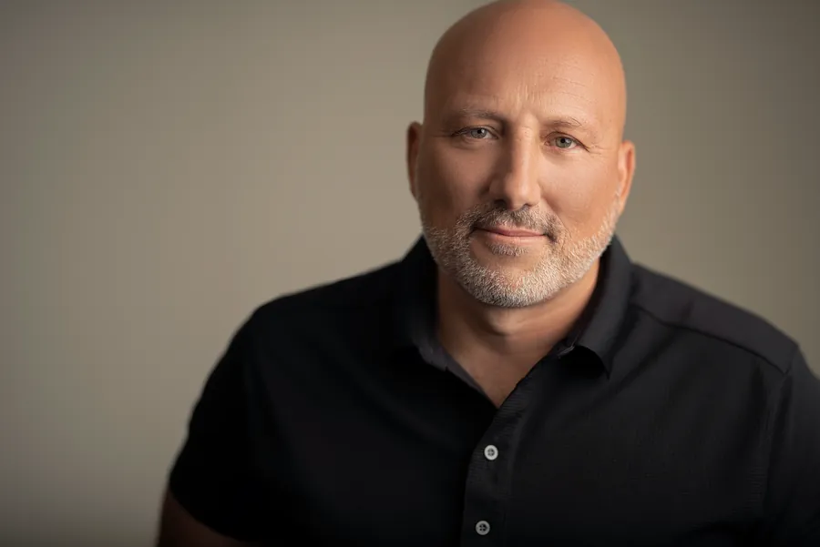 Bald man with a gray beard in a black shirt against a neutral gray backdrop, corporate headshot in Nashville