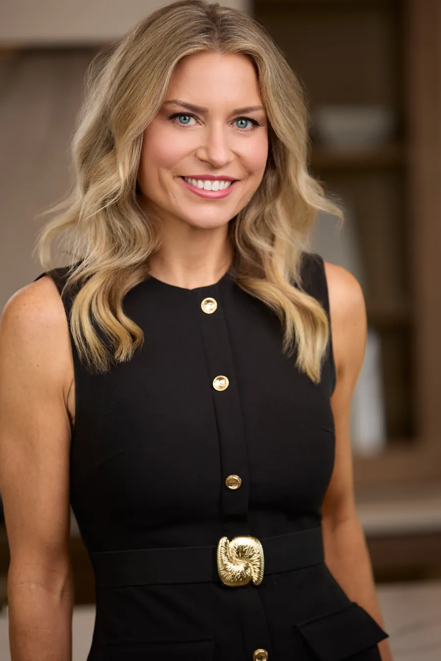 Blonde woman in a black dress with gold buttons, brand portrait