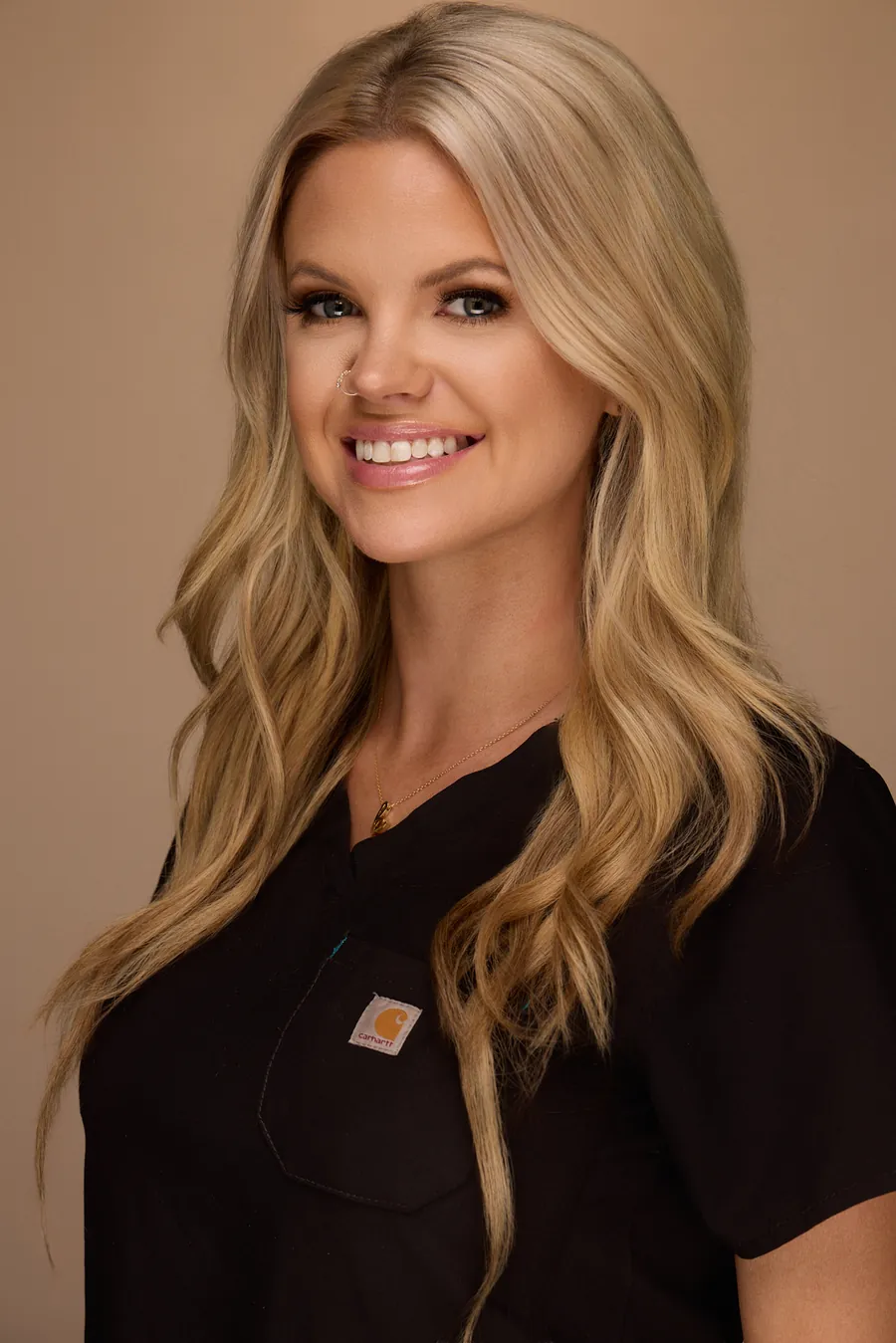 Blonde woman in a black top against a warm backdrop, team portrait