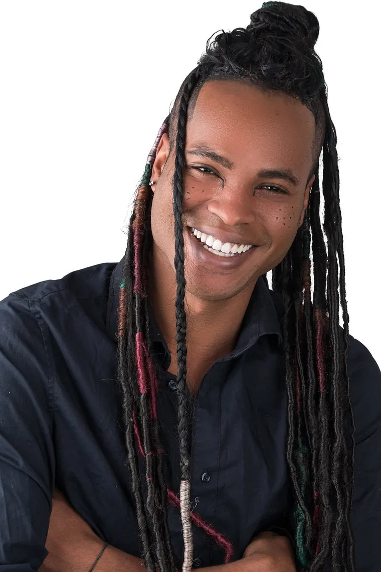 Commercial acting headshot of a smiling man with long locs in a dark button-up shirt against a white background