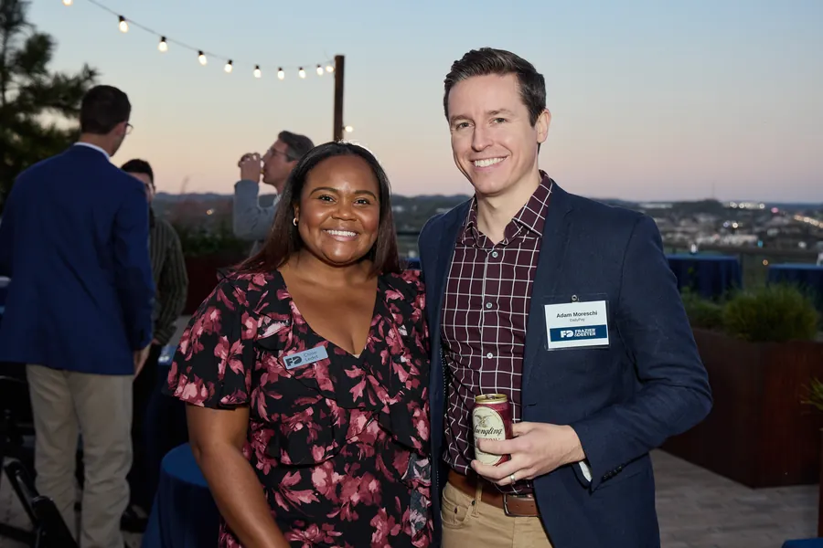 Couple posing under rooftop string lights at dusk, Frazier & Deeter Nashville open house