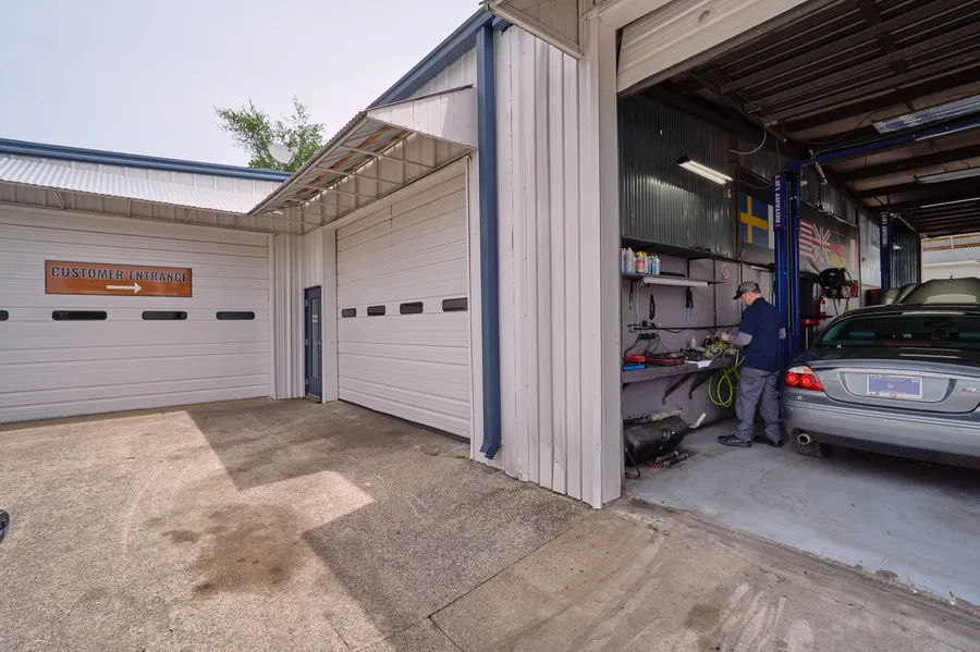 Exterior of the Wursters auto shop with a mechanic working in an open garage bay