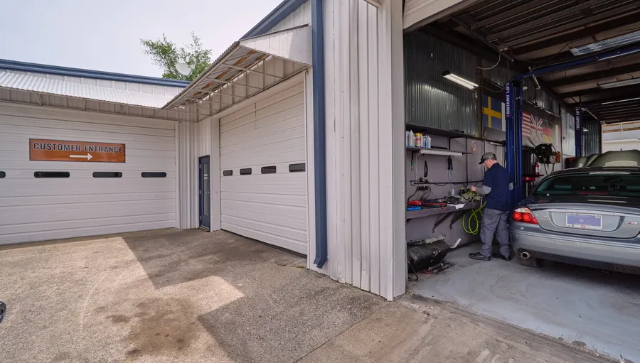 Exterior of the Wursters auto shop with a mechanic working in an open garage bay
