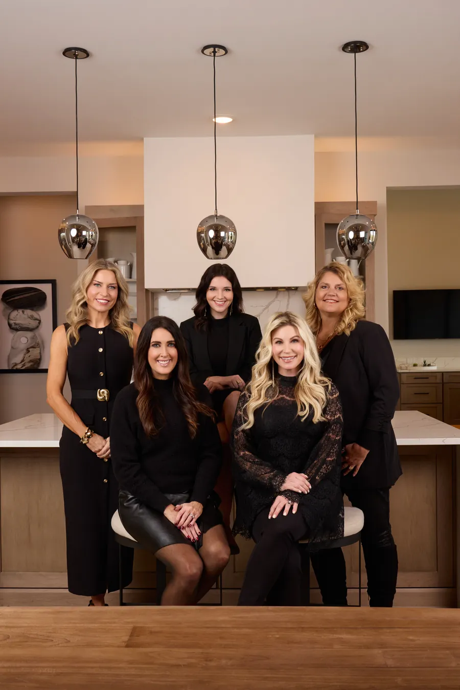 Five women posed together in a modern kitchen, OneLuxe team branding photo