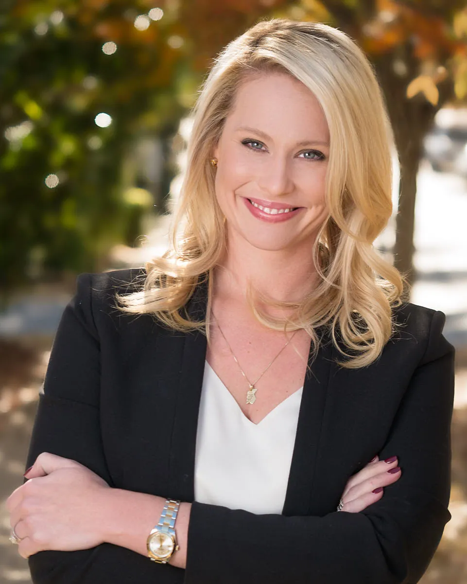 Smiling blonde woman in a black blazer with her arms crossed, professional headshot in Franklin, TN