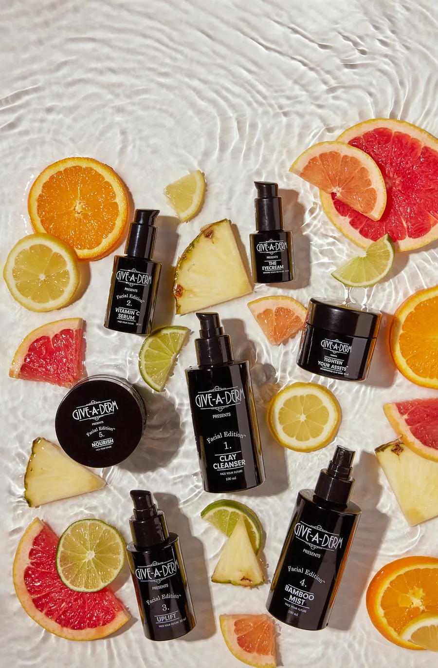 Give-A-Derm skincare bottles on a citrus flat lay, product photography