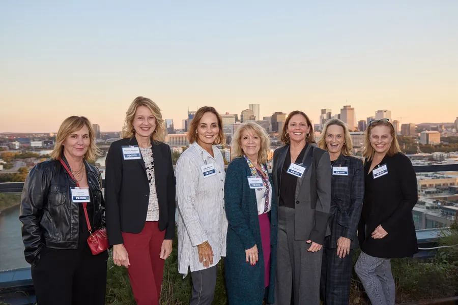 Group of women posing with the Nashville skyline at golden hour, Frazier & Deeter open house