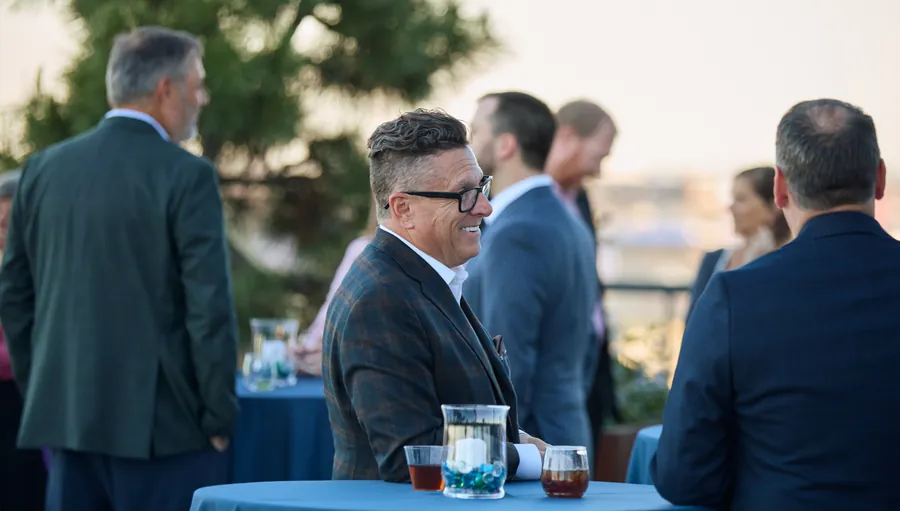 Guest smiling at a rooftop table overlooking the river at the Frazier & Deeter Nashville open house