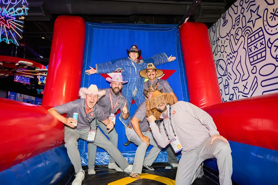 Guests in cowboy hats and padded suits posing on an inflatable at the ECRS Ignite 2026 closing party