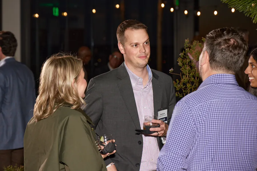 Guests talking under string lights at night, Frazier & Deeter Nashville open house