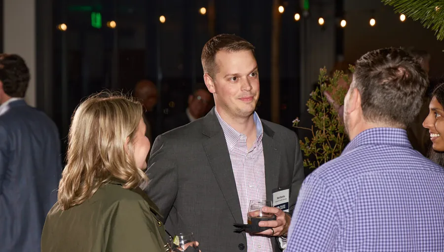 Guests talking under string lights at night, Frazier & Deeter Nashville open house