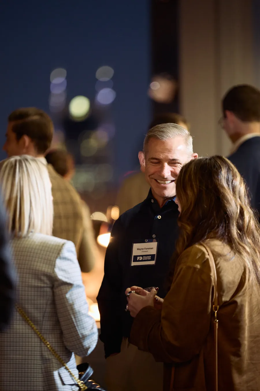 Guests talking with the city lights behind them at the Frazier & Deeter Nashville open house