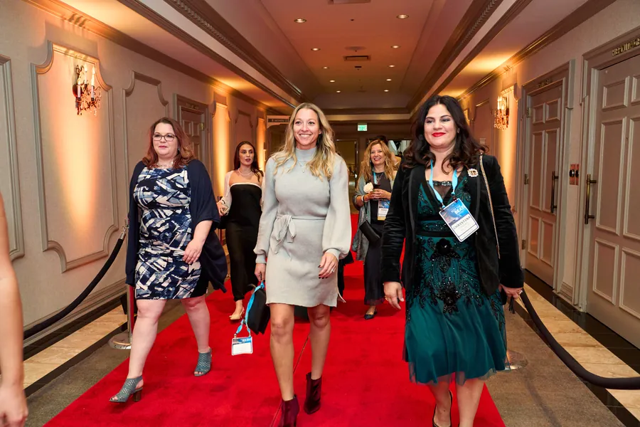 Guests walking a red carpet down a hotel hallway at an awards event