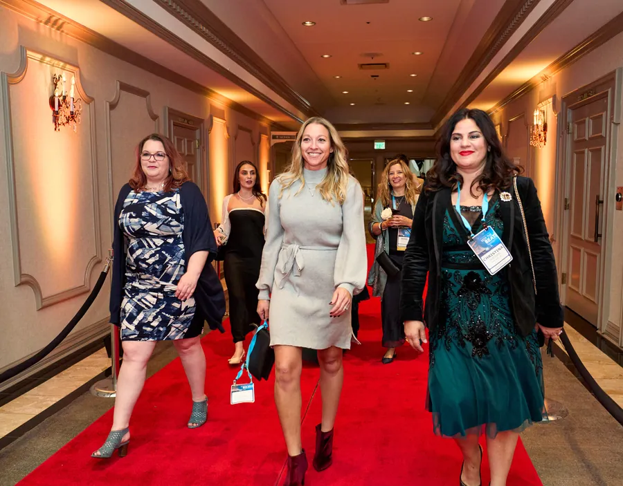 Guests walking a red carpet down a hotel hallway at an awards event