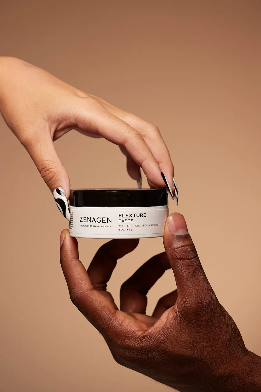 Hands holding a jar of Zenagen paste against a tan background, rebrand campaign