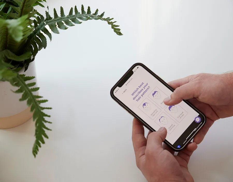 Hands holding a phone beside a fern, product photo from the Zenagen rebrand campaign