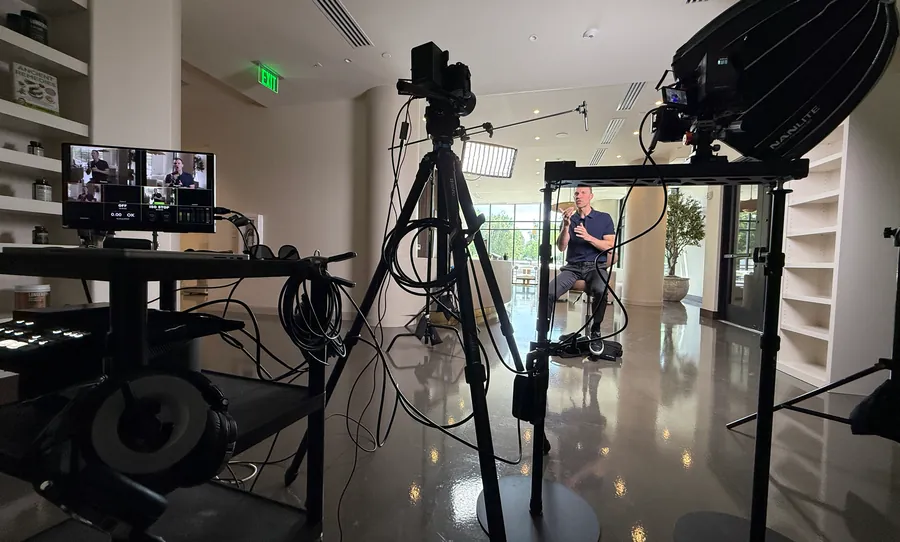 Interview video setup with a camera, softbox, and umbrella lighting in an office lobby