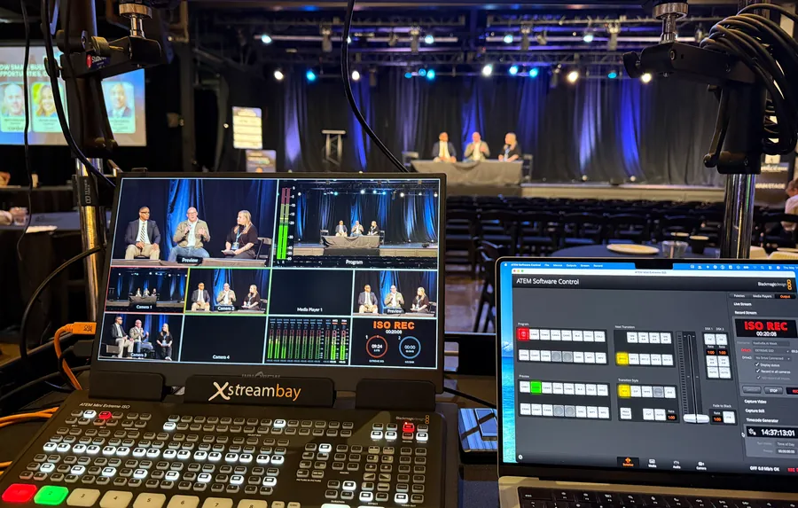 Live event production control room with switcher monitors and a lit stage in the background