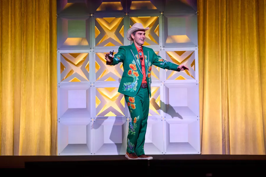 Man in a green suit and hat performing on a stage