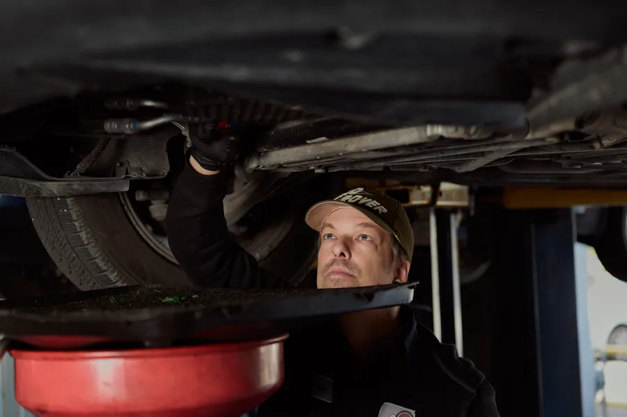 Mechanic in a ballcap looking up while working underneath a lifted vehicle, Wursters branding photo