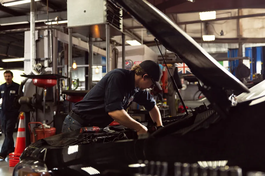 Mechanic working under the open hood of a car in the Wursters shop