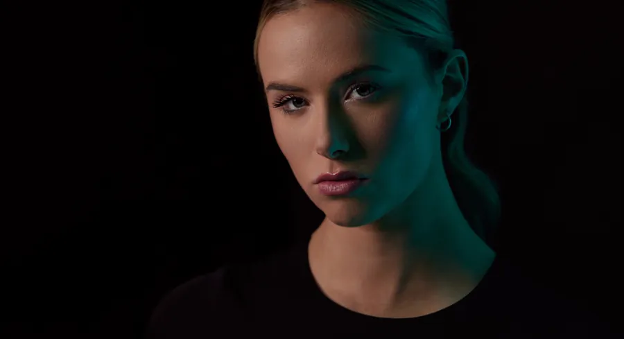 Moody actor headshot of a woman lit in teal against a black background