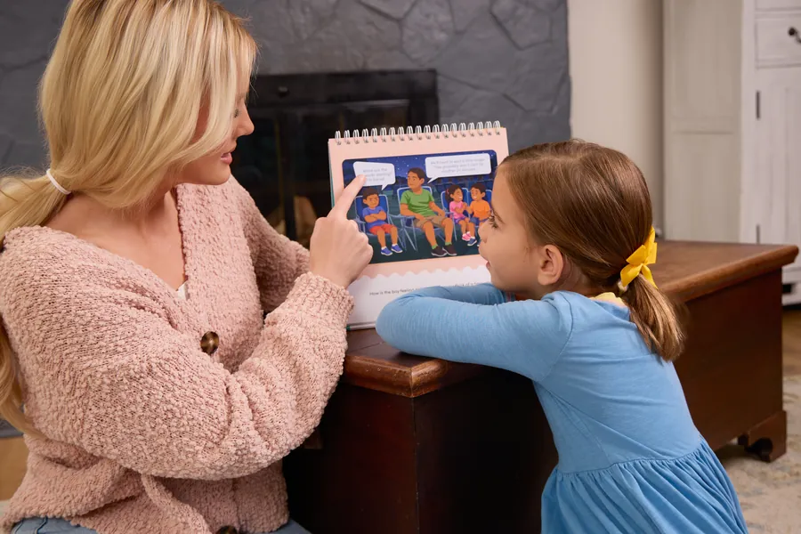 Mother and daughter reading an activity book by the fireplace