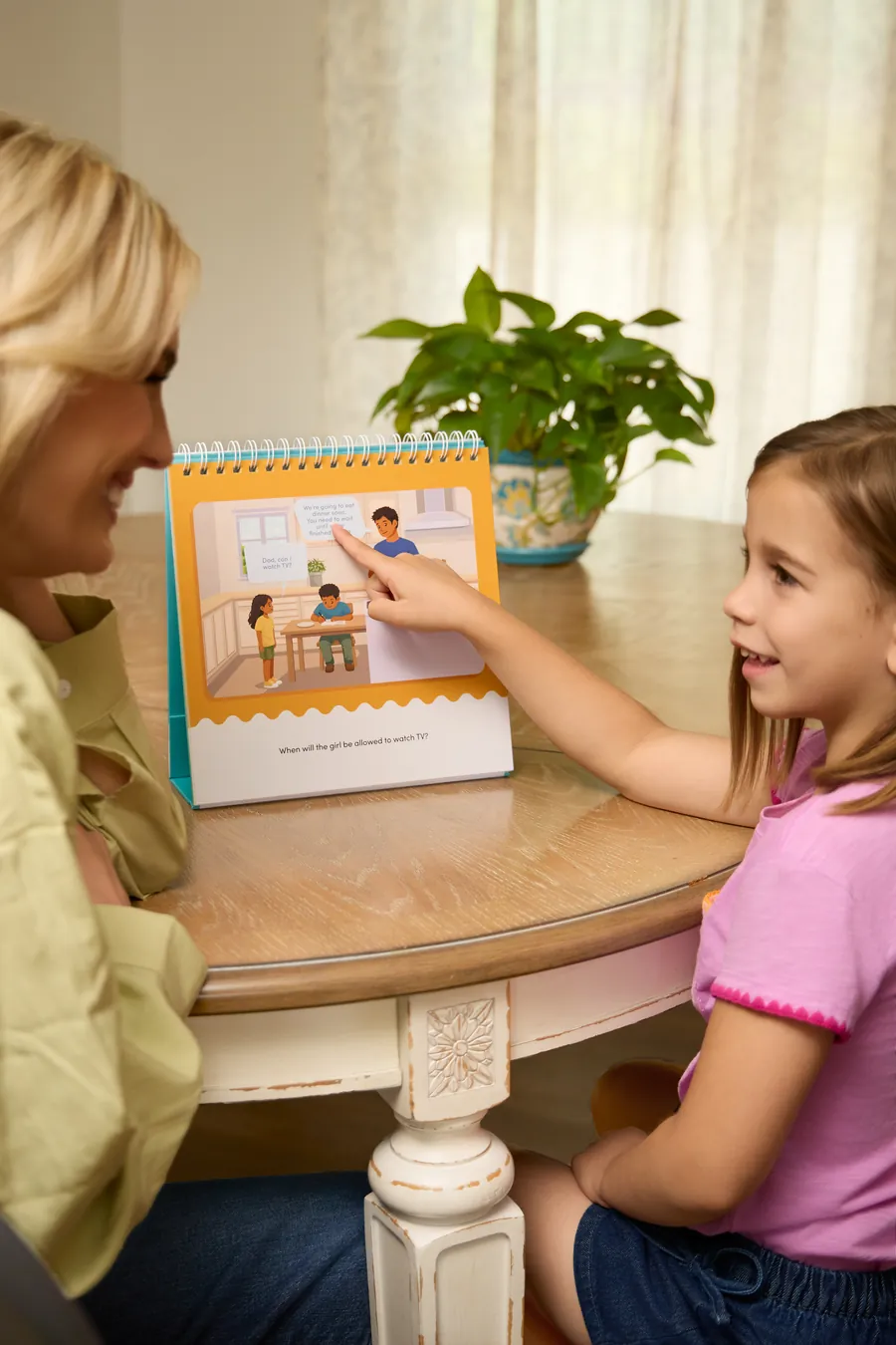 Mother and daughter reading the Waiting For Things We Want activity book together at a kitchen table
