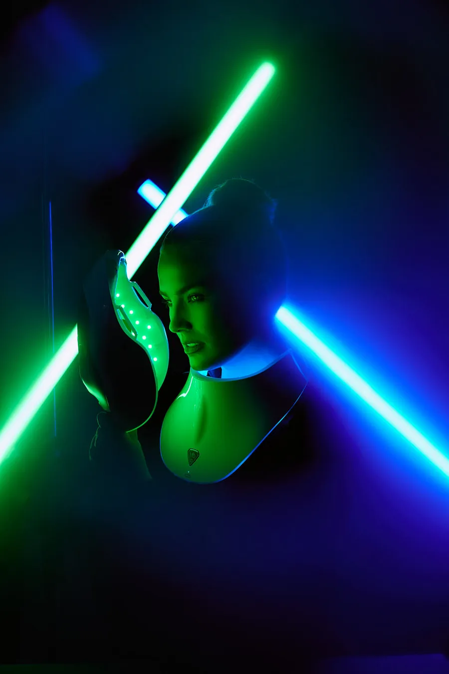 Person lit by green and blue neon light bars in a dark studio, branding session for Artemis