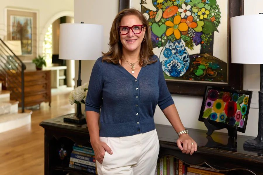 Portrait of the art consultant standing beside a colorful floral painting in a client's home