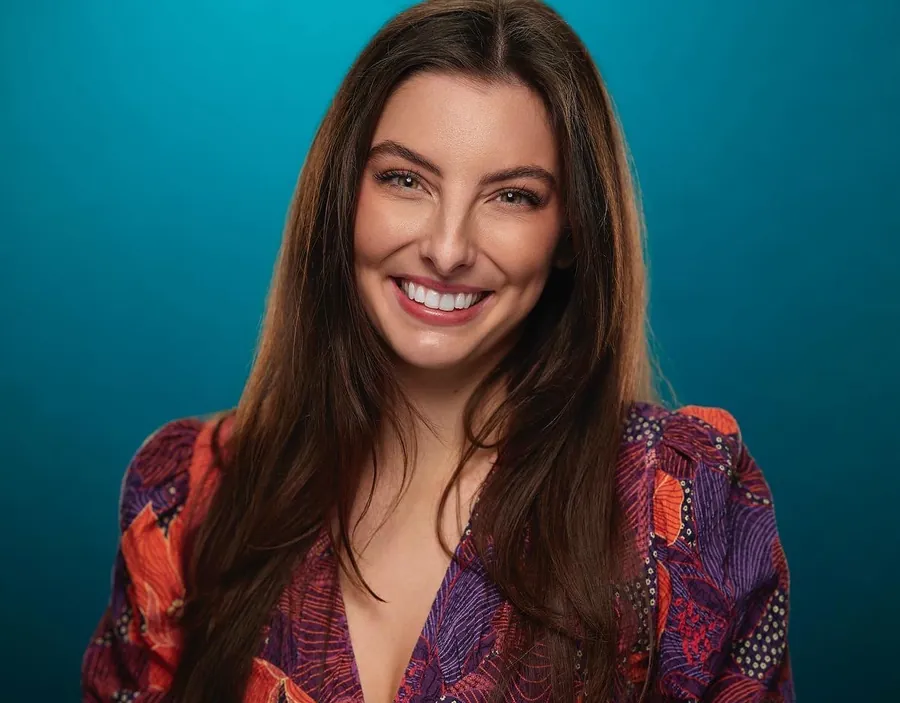 Smiling woman in a patterned top against a teal background, professional headshot