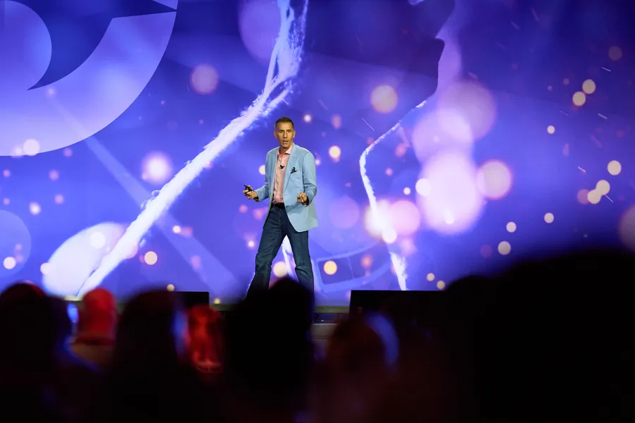 Speaker on a stage lit in purple and blue at a corporate event