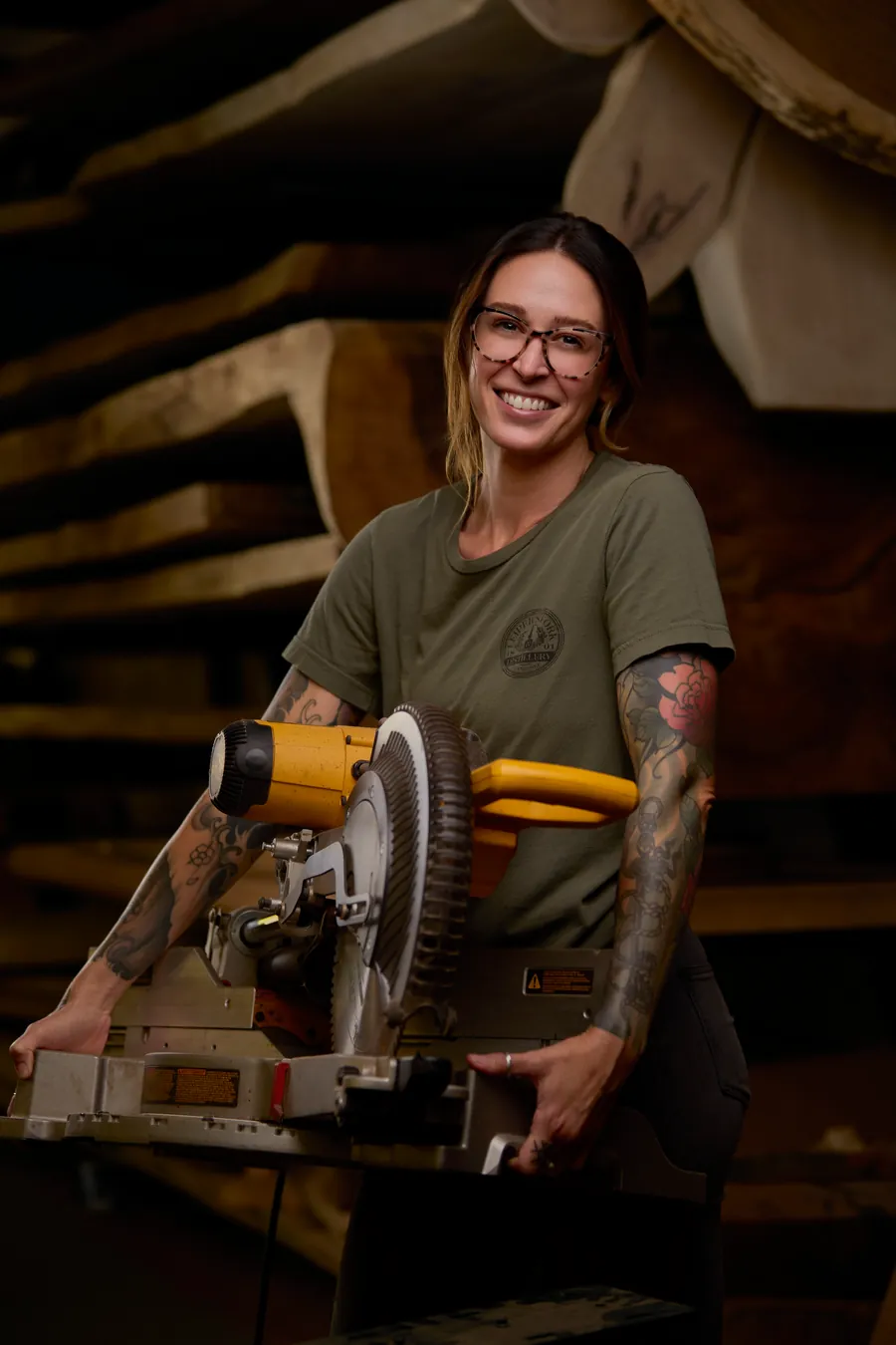 Tattooed woman operating a miter saw in the workshop, branding photo