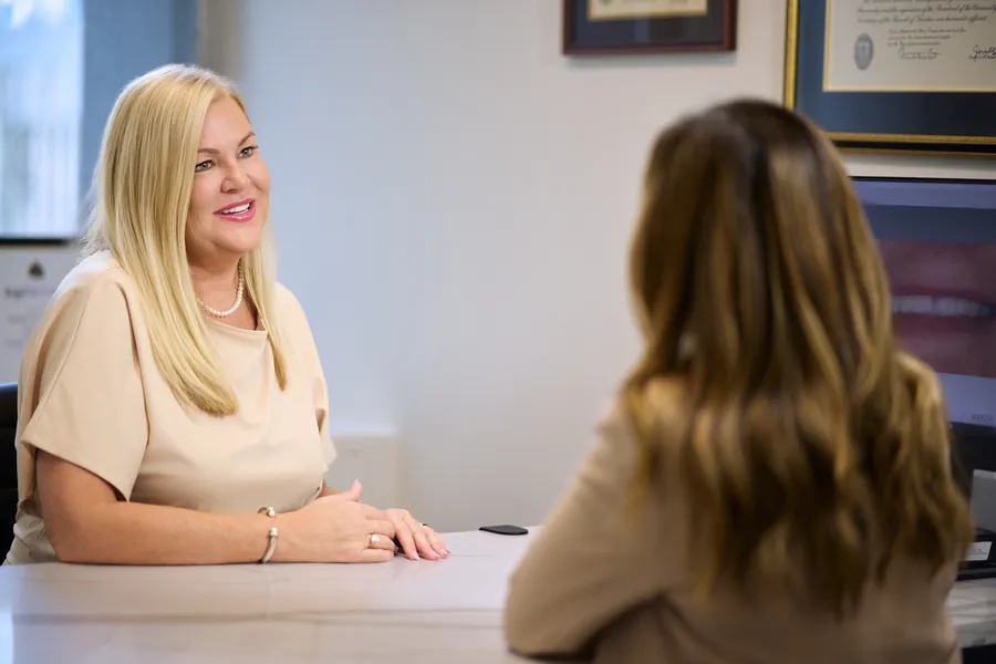 Two women talking across a desk in an office, brand lifestyle photography