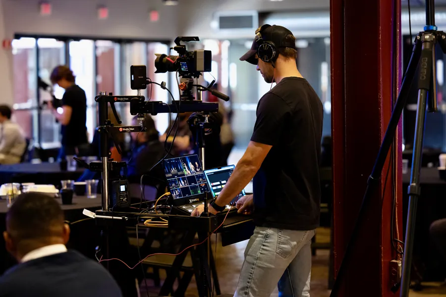 Video crew filming with a handheld gimbal rig at an event