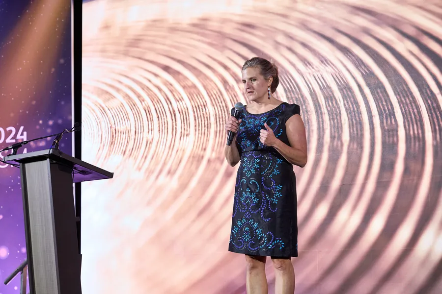Woman in a blue dress speaking on stage at a conference