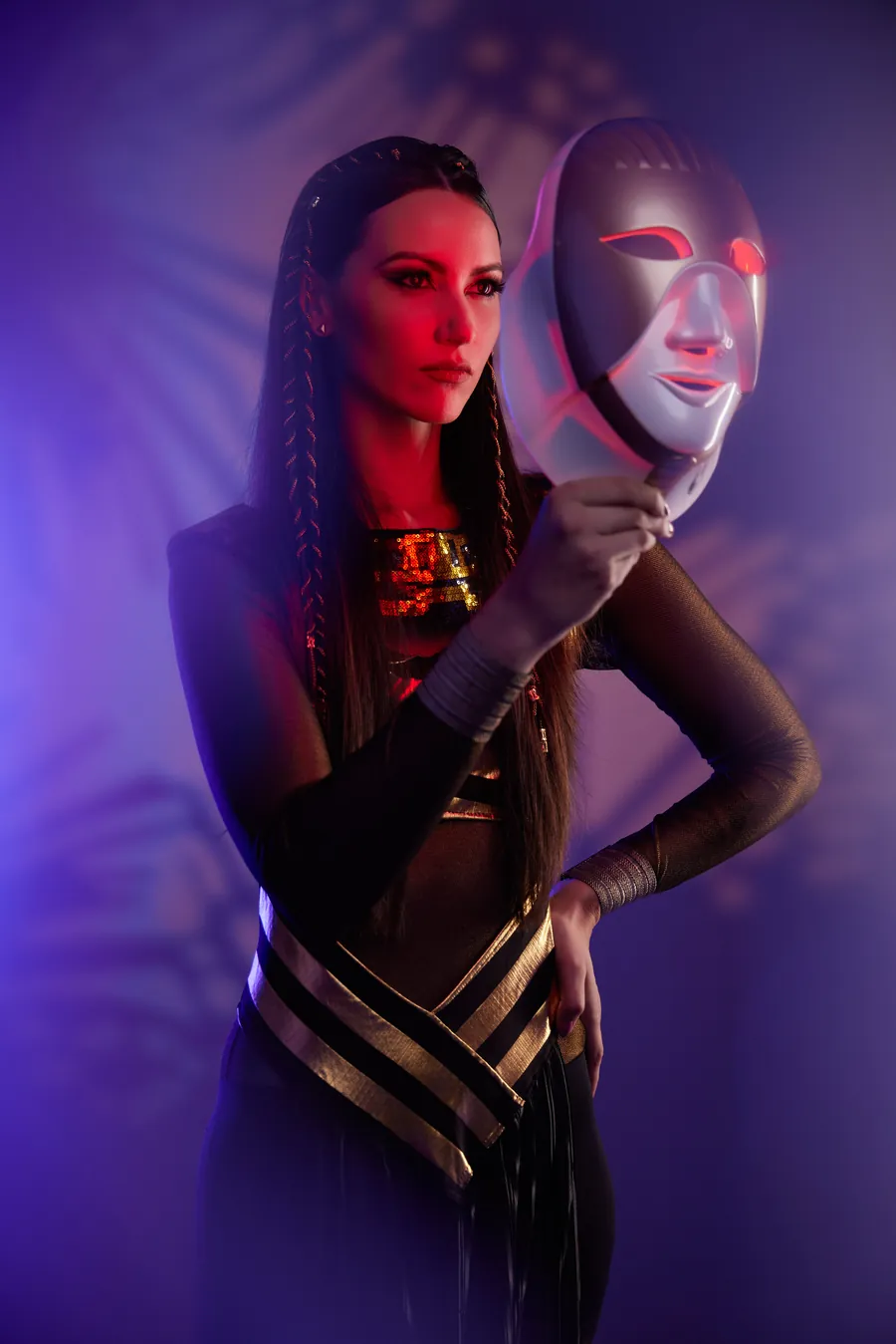 Woman in an Egyptian-inspired outfit holding a mask against a purple backdrop, Cleopatra Mask launch