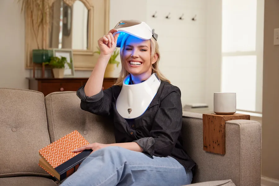 Woman on a couch wearing an LED light therapy mask, lifestyle photo for Artemis