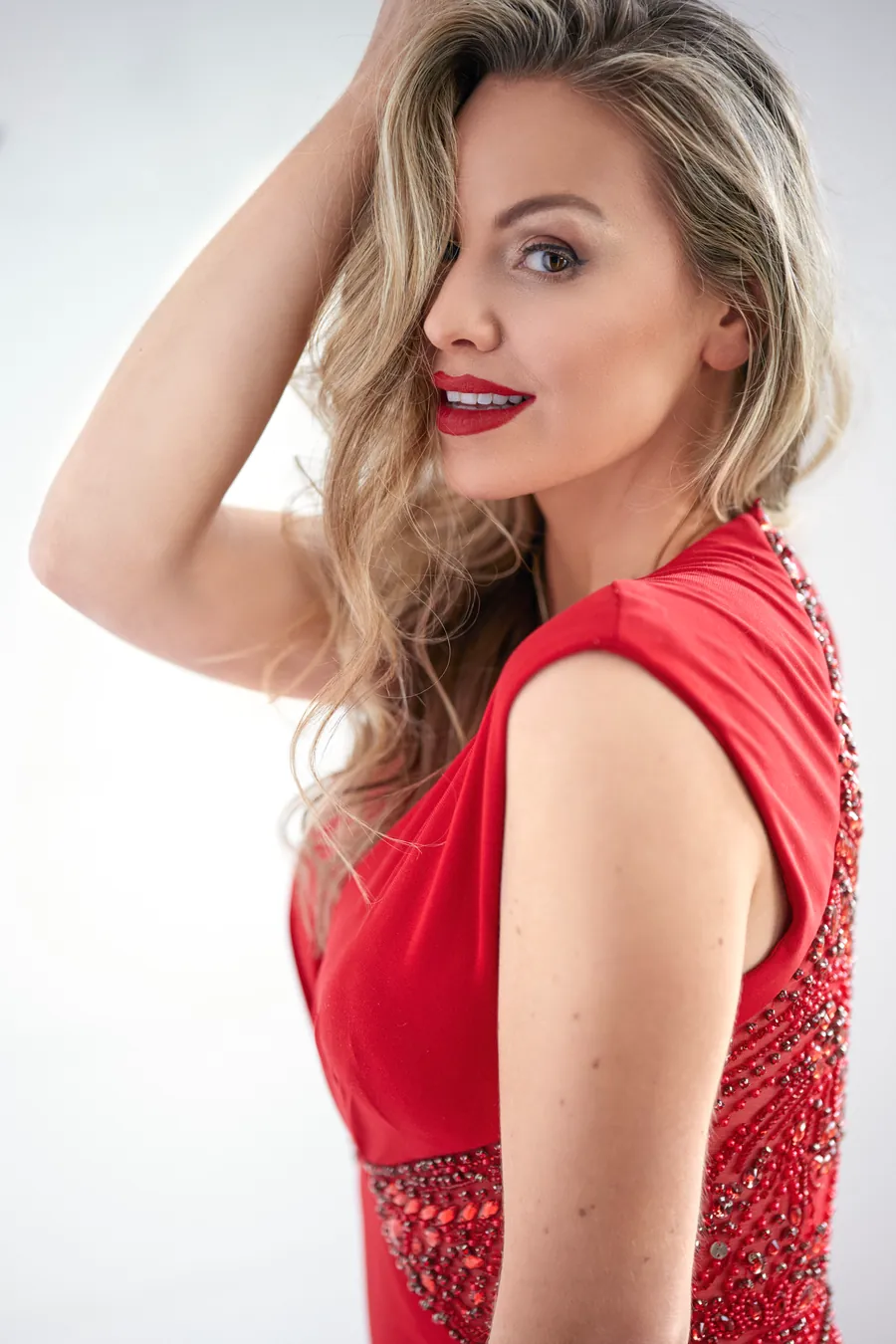Woman with blonde hair in a red dress against a white background, portrait